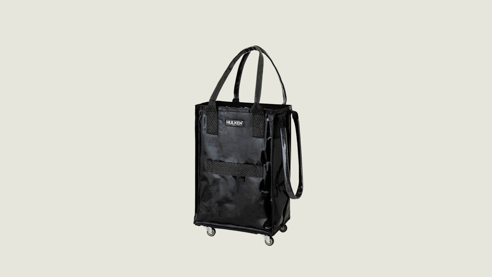 Black carry on bag with wheels on a light gray background